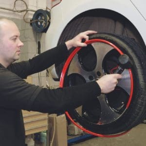 Man fitting a set of Red AlloyGator Wheel and Tyre Protectors to a White Volkswagen Car
