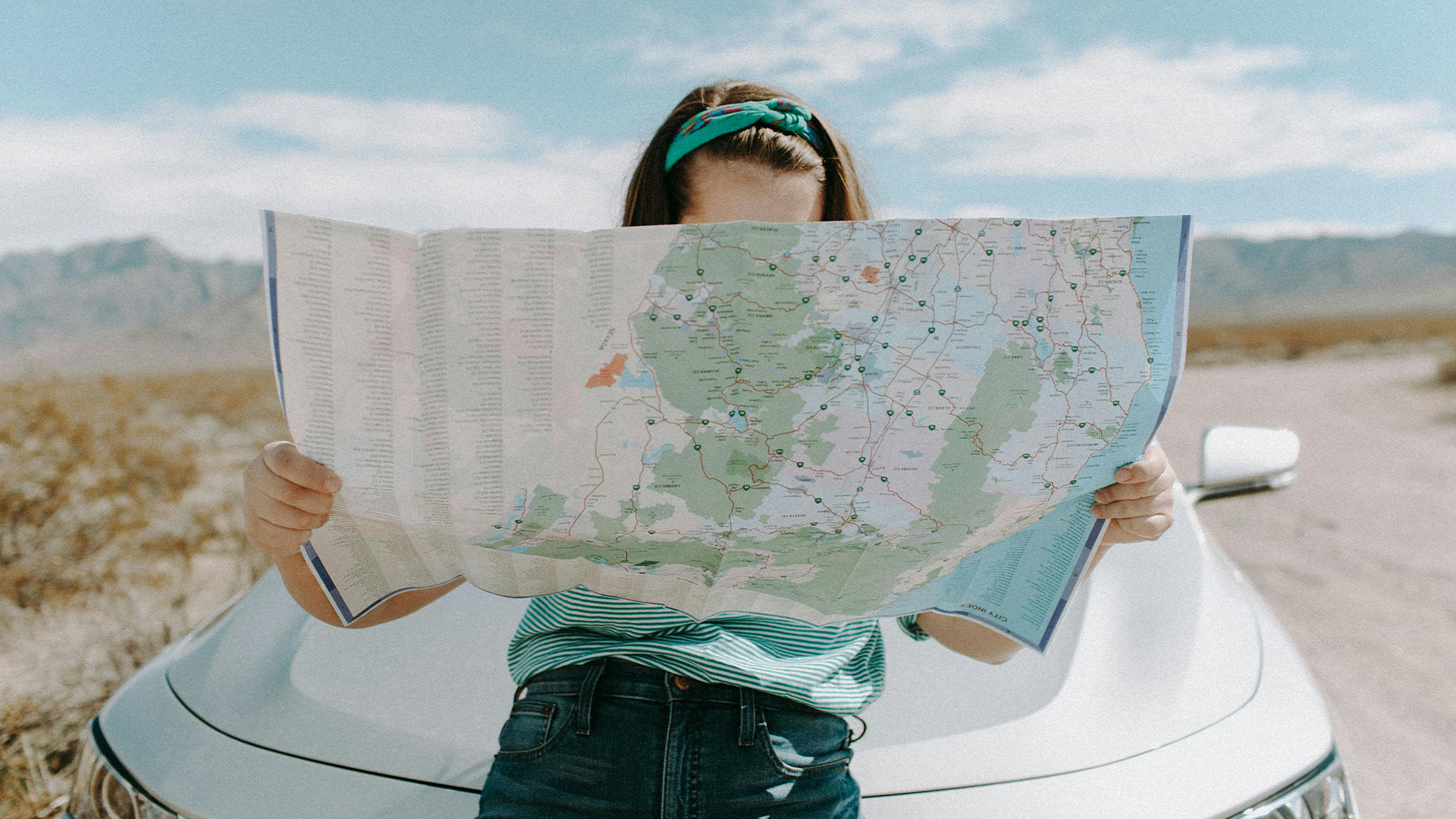 Woman holding a road map, symbolising a summer road trip.