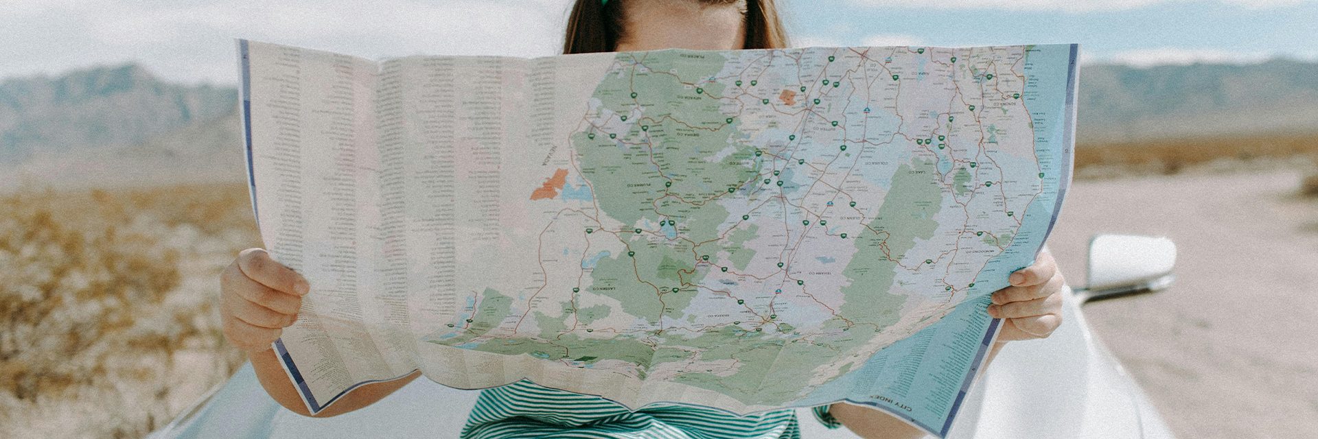 Woman holding a road map, symbolising a summer road trip.